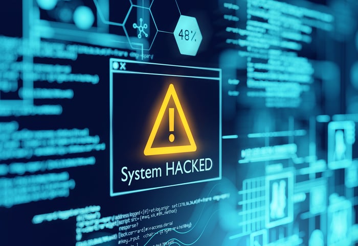 A computer screen with data displays and an alert that the system has been hacked.