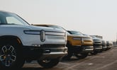 Line of Rivian trucks in a parking lot. IS RIVN