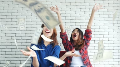 Two people laughing as money falls down on them from above