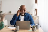 person talking on the phone and looking at a laptop