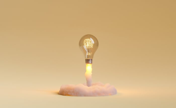A lightbulb taking off like a rocket on a golden background.