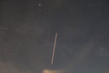 Long exposure photograph of a line of recently deployed Starlink satellites in the sky.