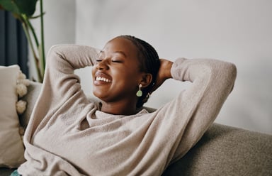 Relaxed person sitting on couch with hands behind head