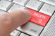 Finger about to press the delete key on a laptop computer