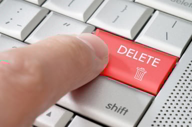 Finger about to press the delete key on a laptop computer