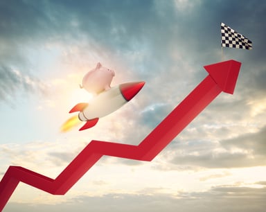 Piggy bank on a rocketship flies along a red stock arrow going up towards a checkered finish line flag.