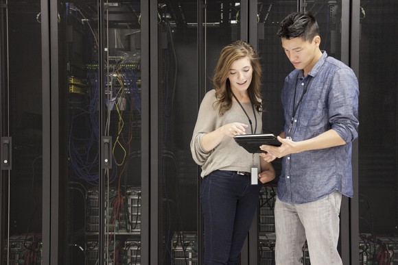 People viewing a mobile device in front of stacks of supercomputers.
