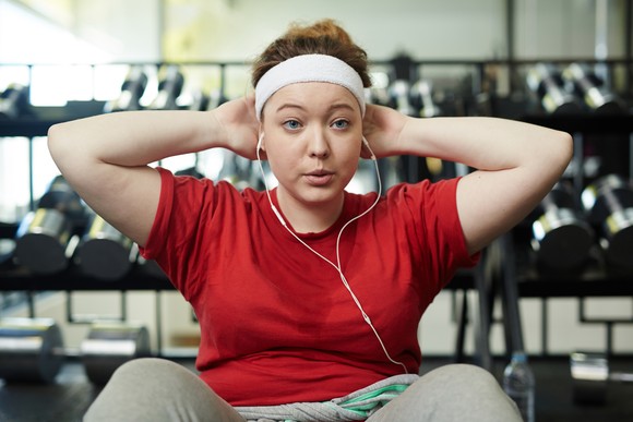 Someone is working out at a gym, with earbuds in.