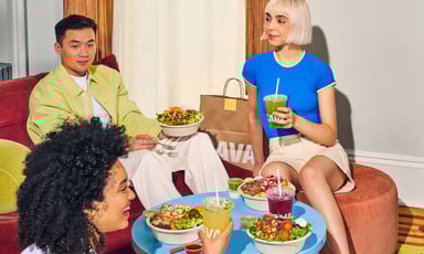 people sitting around a table with food and cava branding in view_CAVA