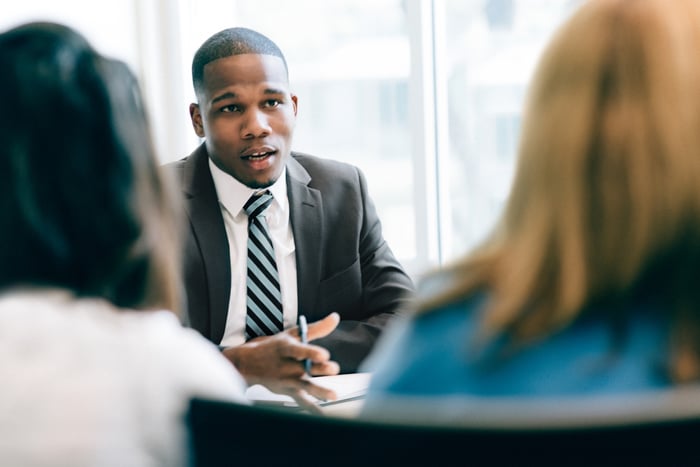 Businessperson talking to two clients.