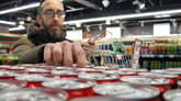 Person taking a red can in a supermarket