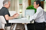 two investors consider a stock with laptop