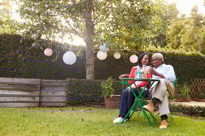 Couple smiling while sitting at a table in the backyard.