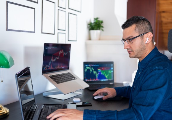 Person using three computer screens for their market analysis.