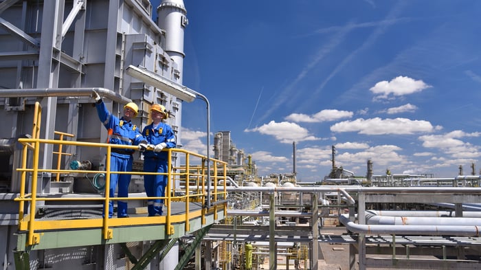 Two people wearing personal protective equipment at an oil refinery.