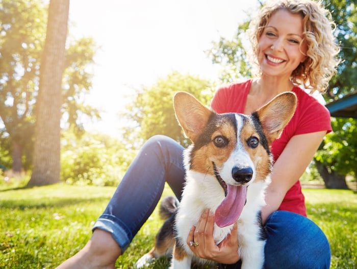 A smiling person takes care of a dog.