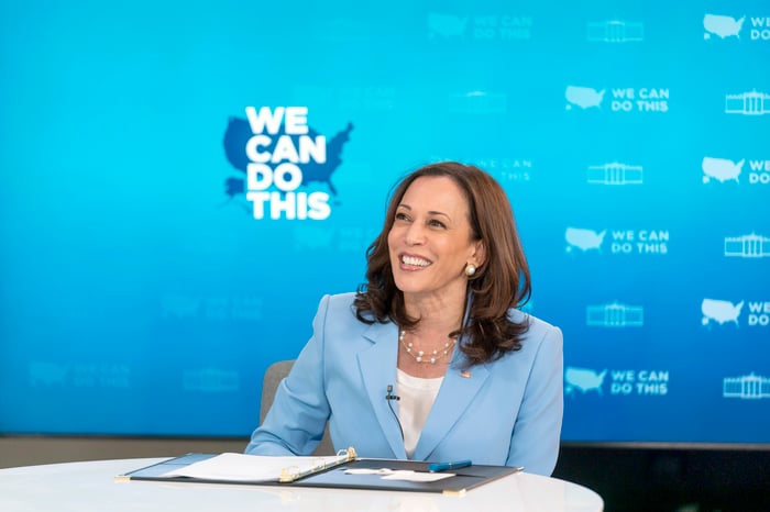 Vice President Kamala Harris sitting behind a desk and smiling.