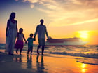 People walking on a beach with a cruise ship in the background.