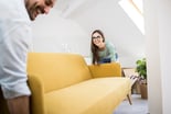 Two people moving a couch into a room