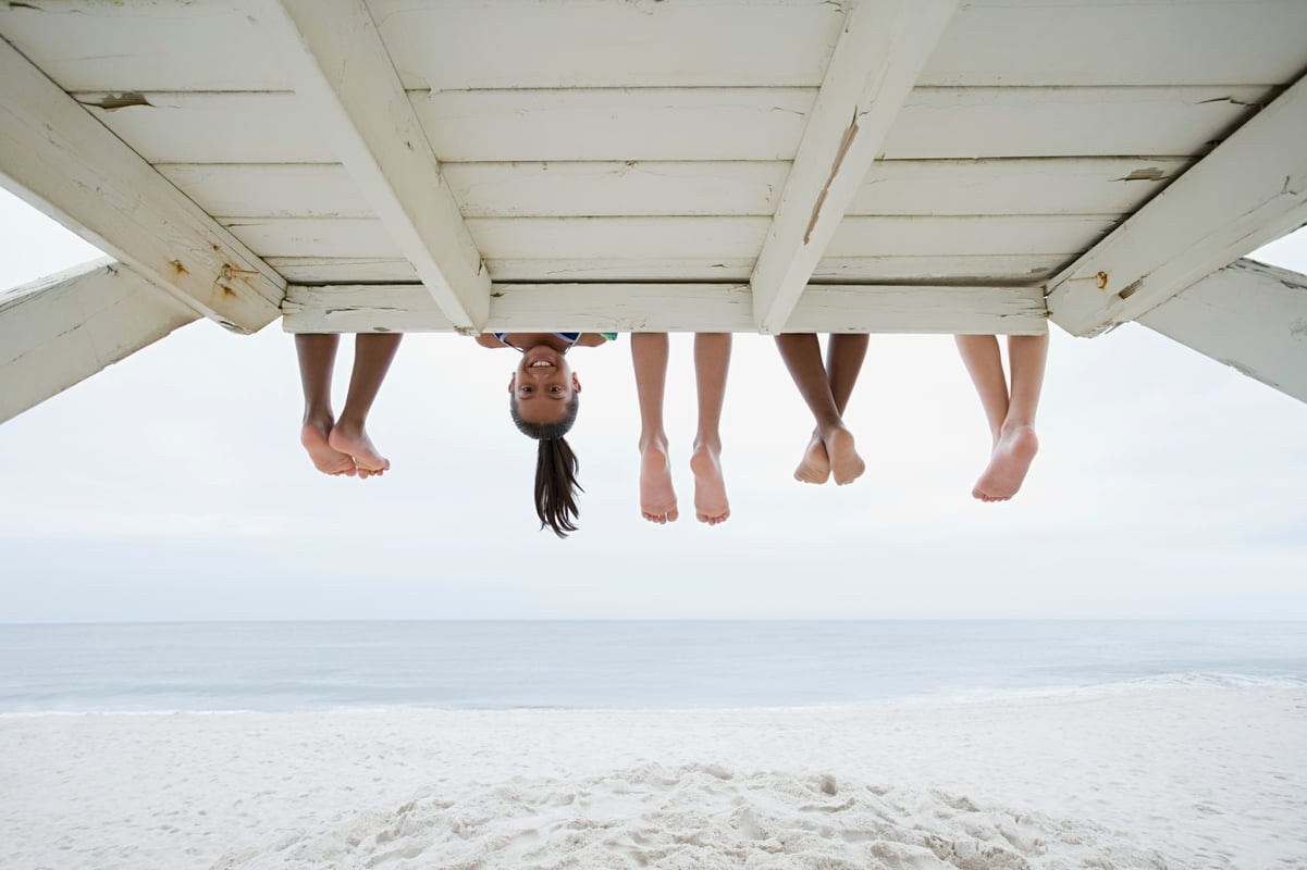 People's legs sticking out from under a boardwalk with one face