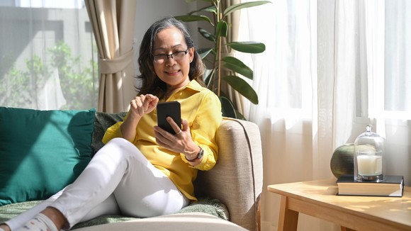 A person on a couch smiles while on a phone.