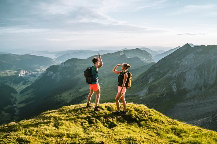 Two people in hiking attire at the top of a mountain range.