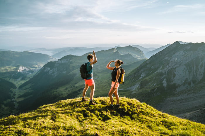 Two people in hiking attire at the top of a mountain range.