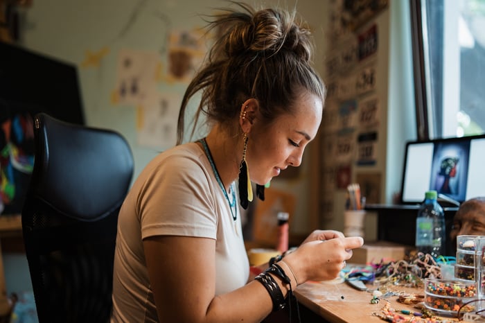 A person makes jewelry in a home workshop.