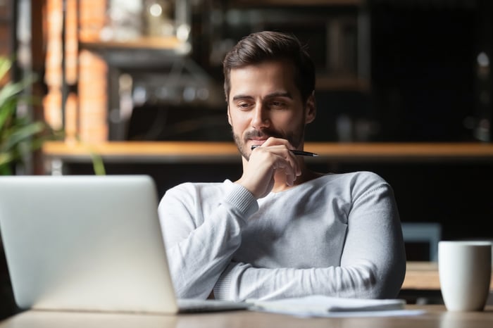 An investor looks pensively at a laptop in an office.