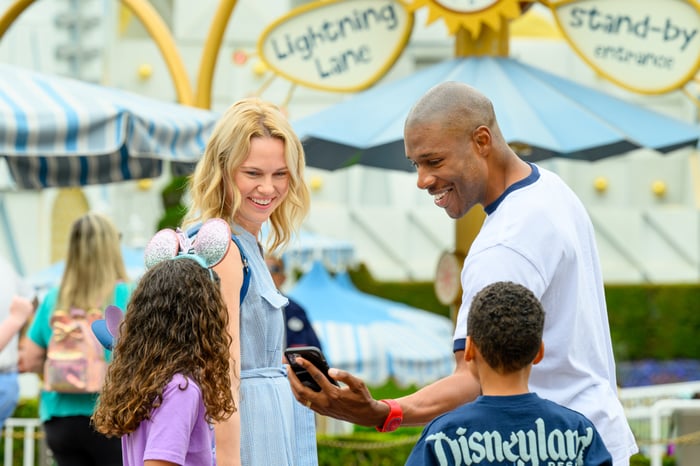 A family checking the Disneyland app before entering the It's a Small World attraction at Disneyland.