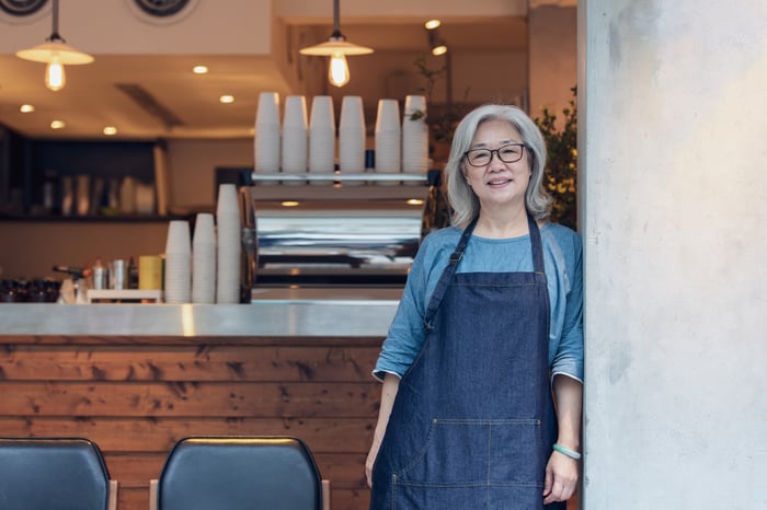 A person wearing an apron in a cafe.