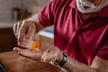 Older man pouring pills into hand GettyImages-1183769634