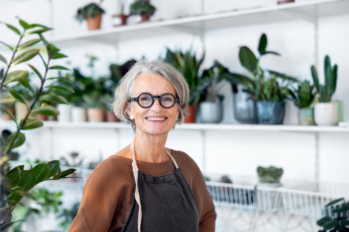 Person standing in a shop surrounded by plants.