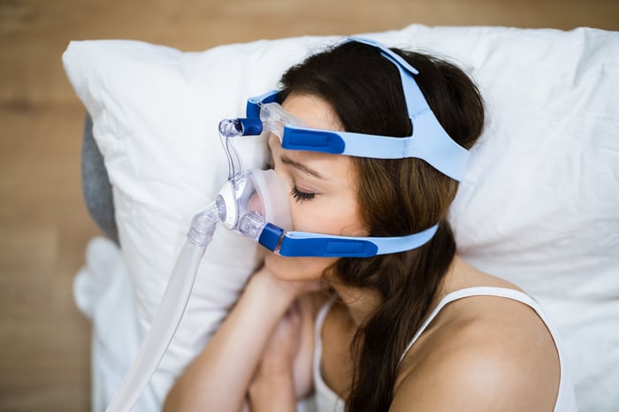 Person sleeping with breathing device over their face.