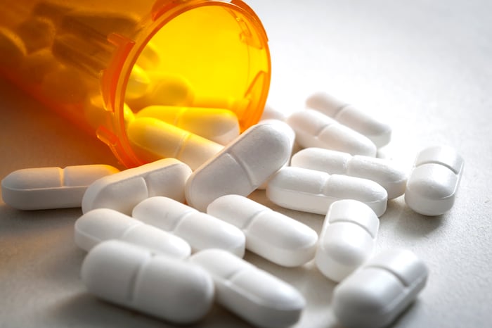 An open pill bottle with pills spilled out.