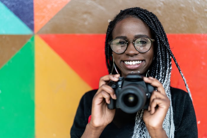 Someone holding a camera and smiling broadly.