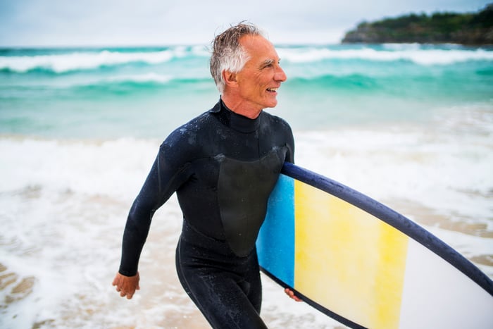 Someone holding a surfboard in front of the ocean.