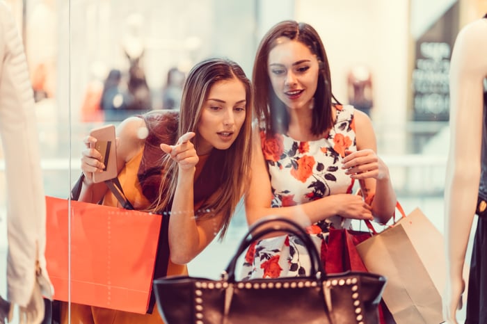 Two consumers shopping for purses. 