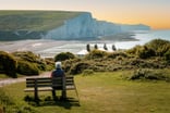 Person sitting on a bench overlooking water.
