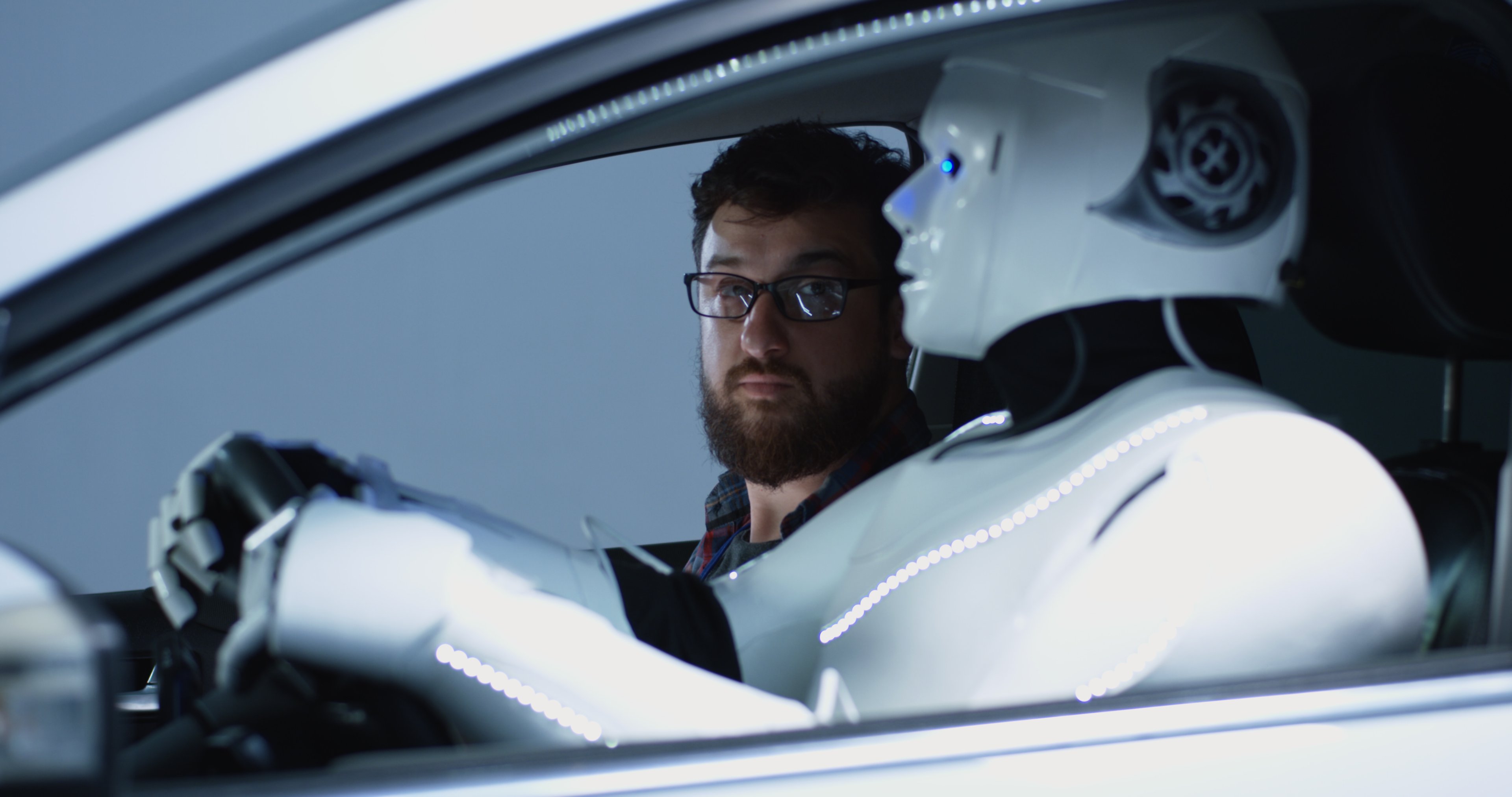 Passenger in car looks skeptically at his robot driver