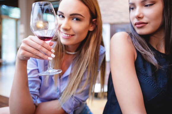 Two people, one with wine glass.