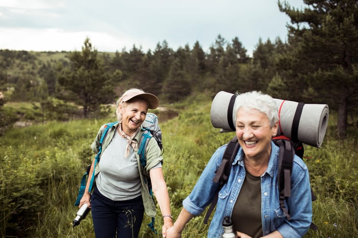 Two people hiking outside and holding hands.