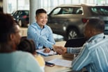 People shaking hands in a car dealership