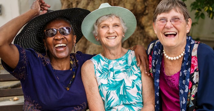 Three people sitting side by side and smiling.