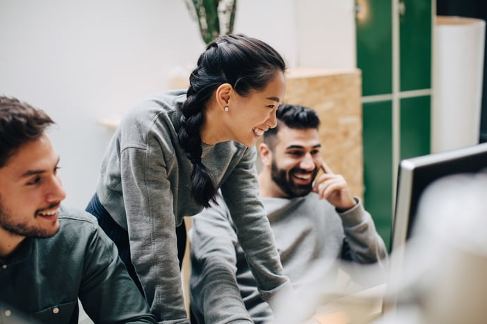 Three investors look at something on a computer in an office.