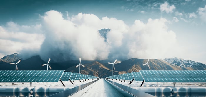 Wind and solar plants with mountains in the background. 