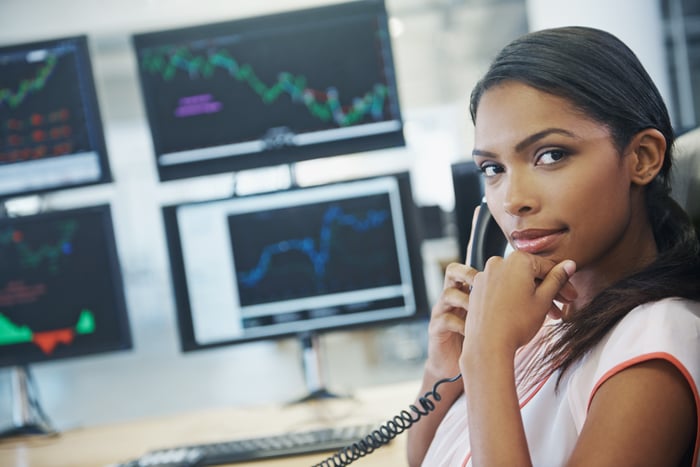 An investor answers the phone in front of several trading screens.