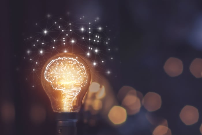 A luminous brain within a lightbulb surrounding by glowing specks.