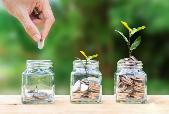 Stacking coins in glass jars that sprout taller saplings based on the number of coins in the jar.