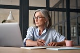 A person at a laptop holding a pen_GettyImages-1281173451